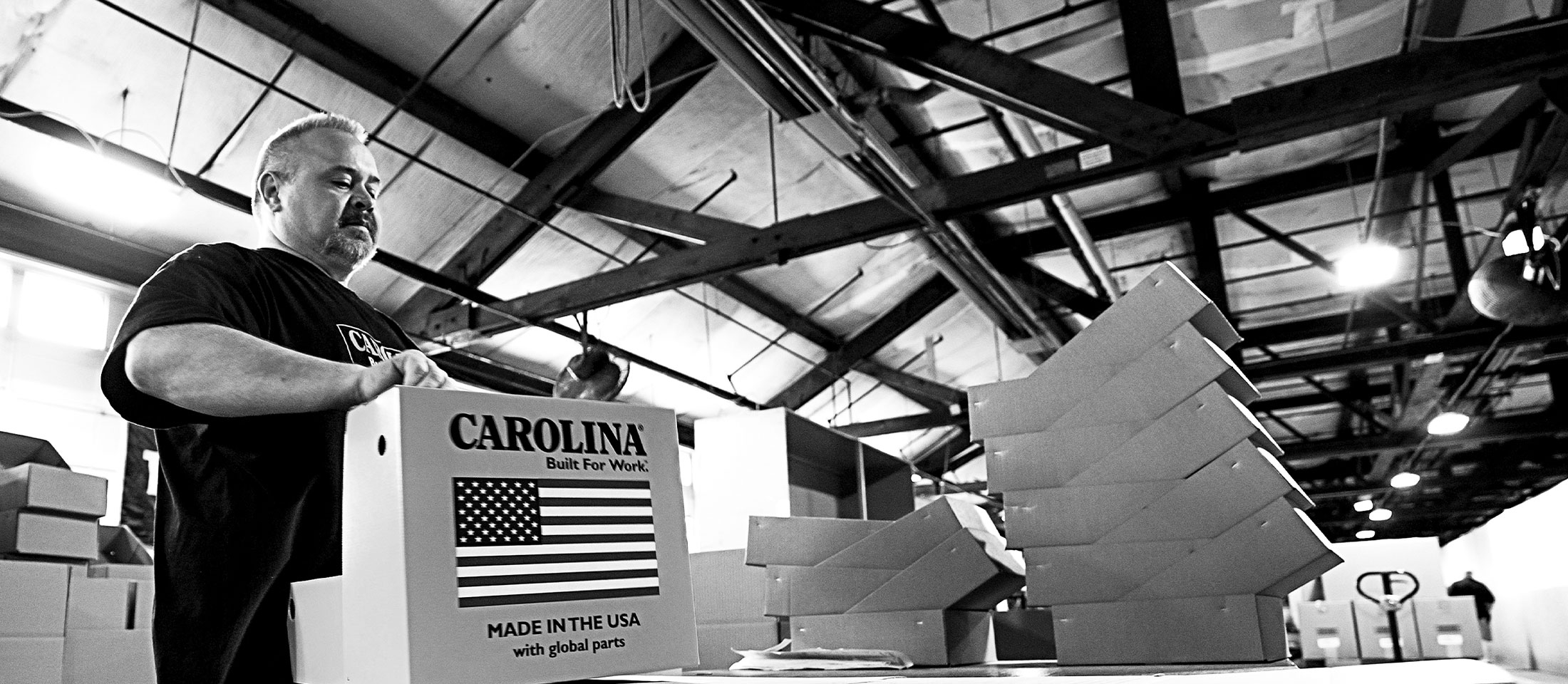 A factory worker boxing up Carolina boots.