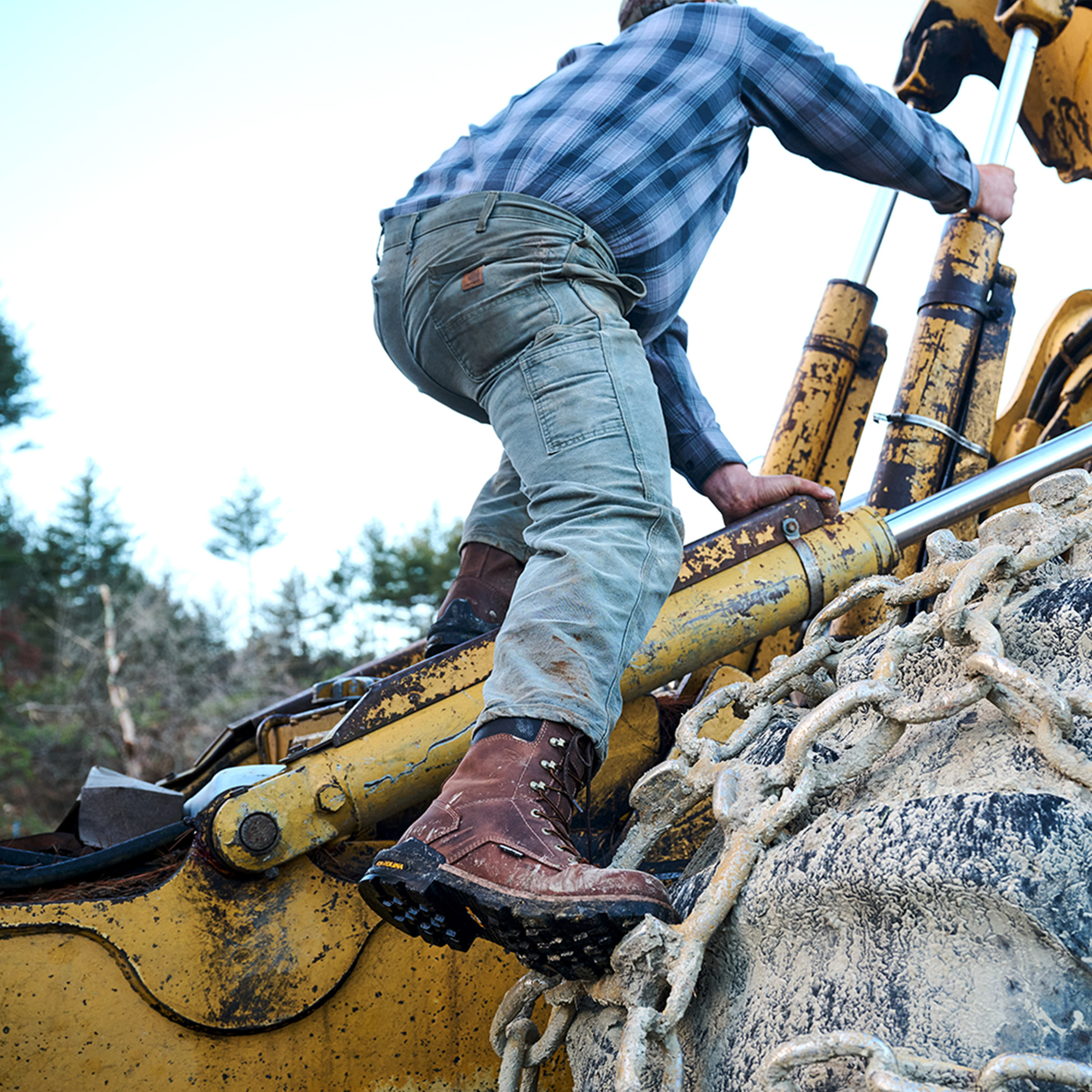 A man climbing on a job site wearing the Cardinal 8" Comp Toe in brown.