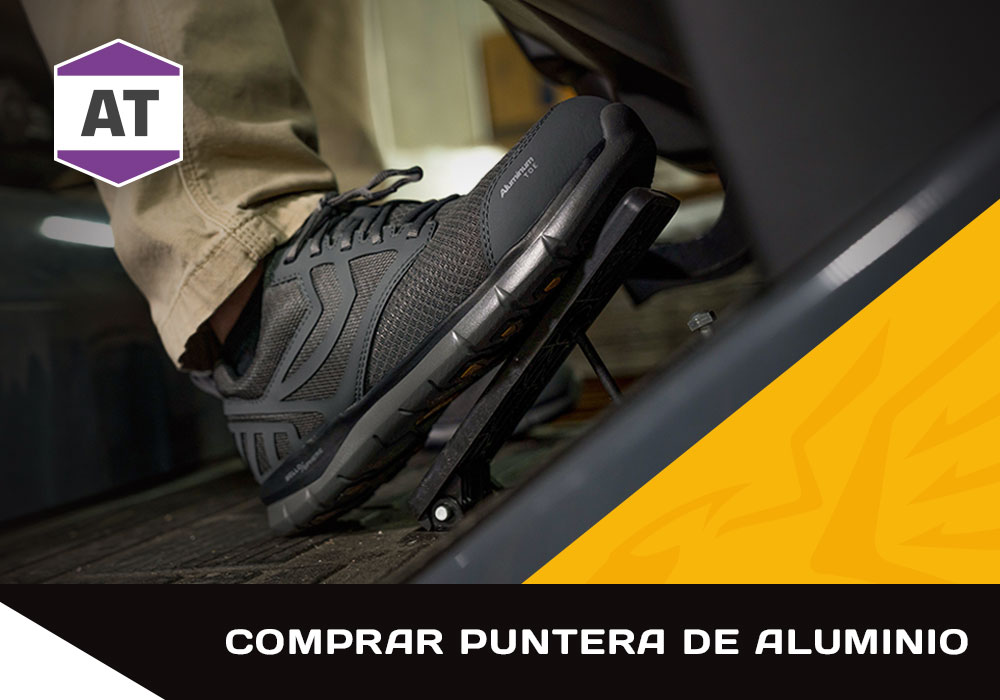 Comprar puntera de aluminio. Insignia de la característica AT. Un hombre trabajando con el zapato de trabajo Gust Lo Aluminium Toe en color negro. Compra puntera de aluminio para hombre.