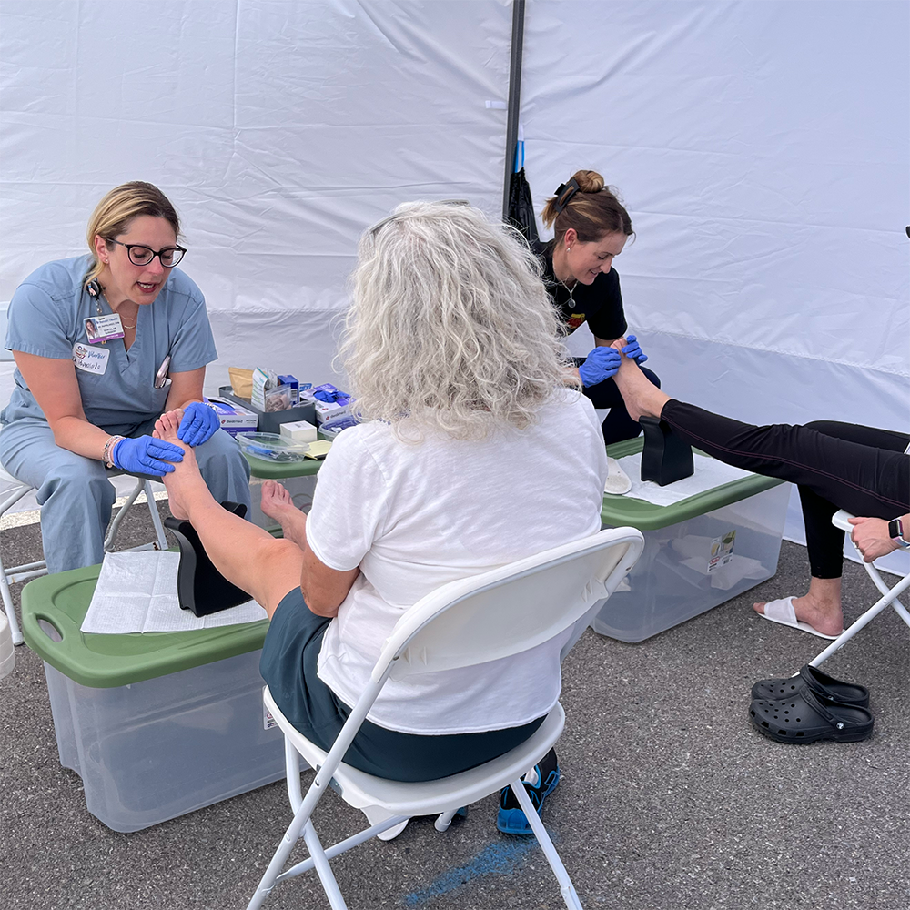 Two women massaging people's feet.