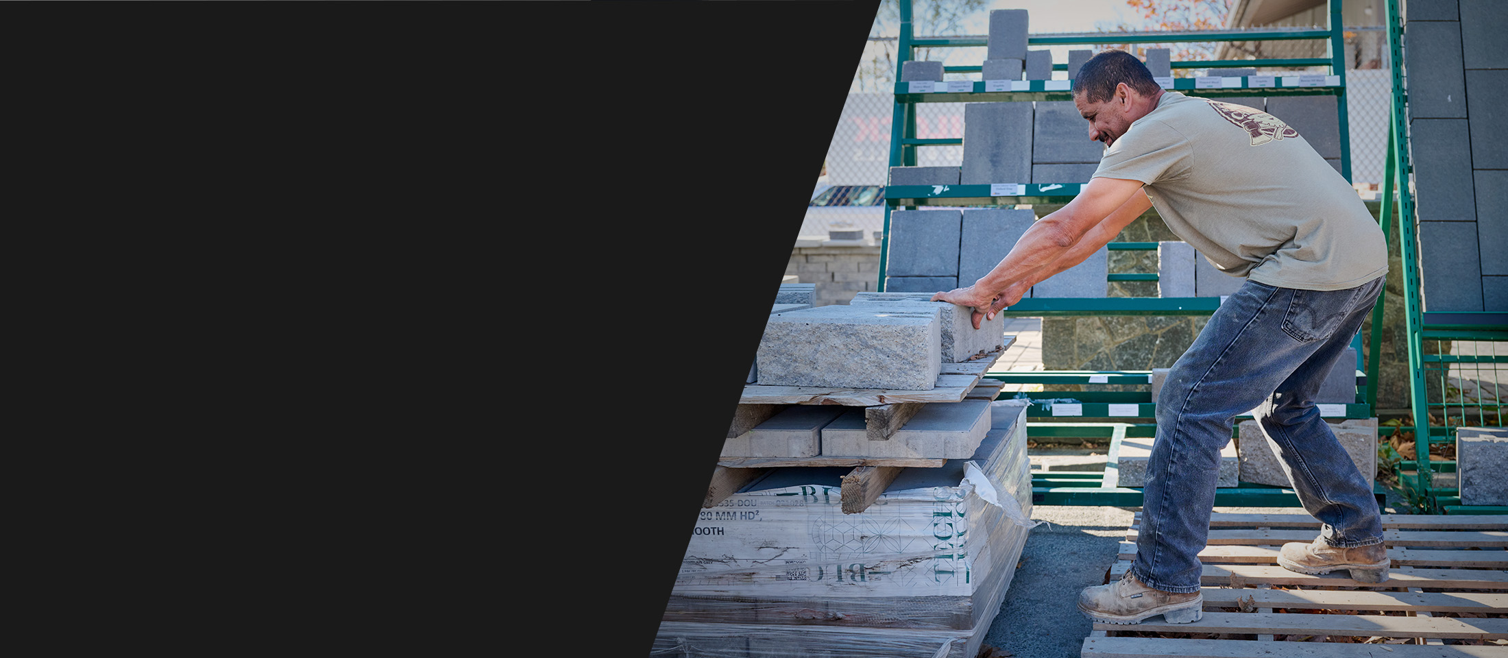 A worker pushing stone blocks and wearing Carolina boots in brown.