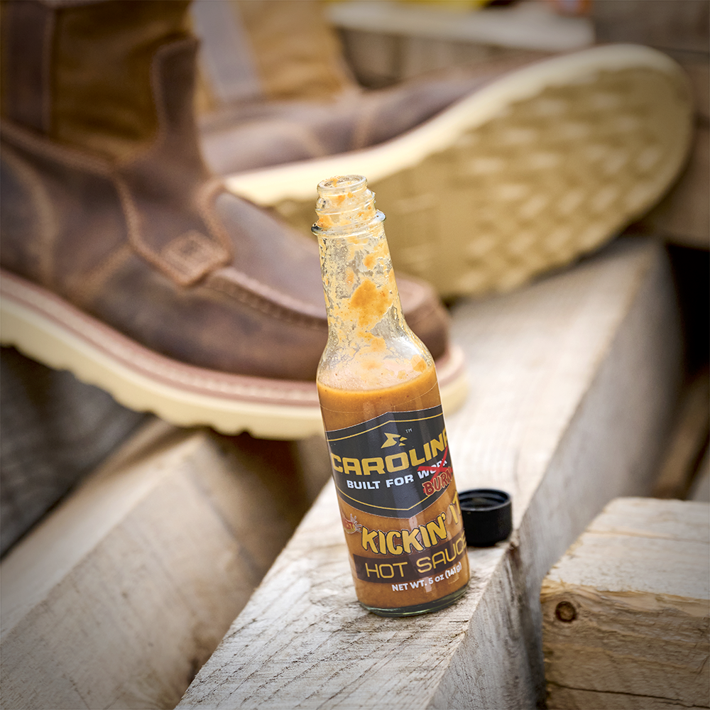 A bottle of Carolina hot sauce with boots in the background.